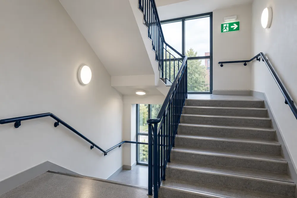 Commercial stairwell with emergency light fittings and an illuminated exit pictogram